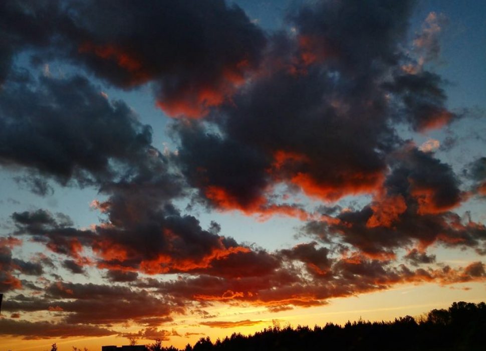 yellow-orange sunset with puffy dark clouds touched with red