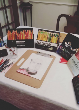 drawingsetup table with artwork surrounded by boxes of colored pencils