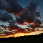 yellow-orange sunset with puffy dark clouds touched with red