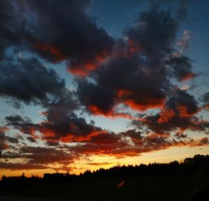 yellow-orange sunset with puffy dark clouds touched with red